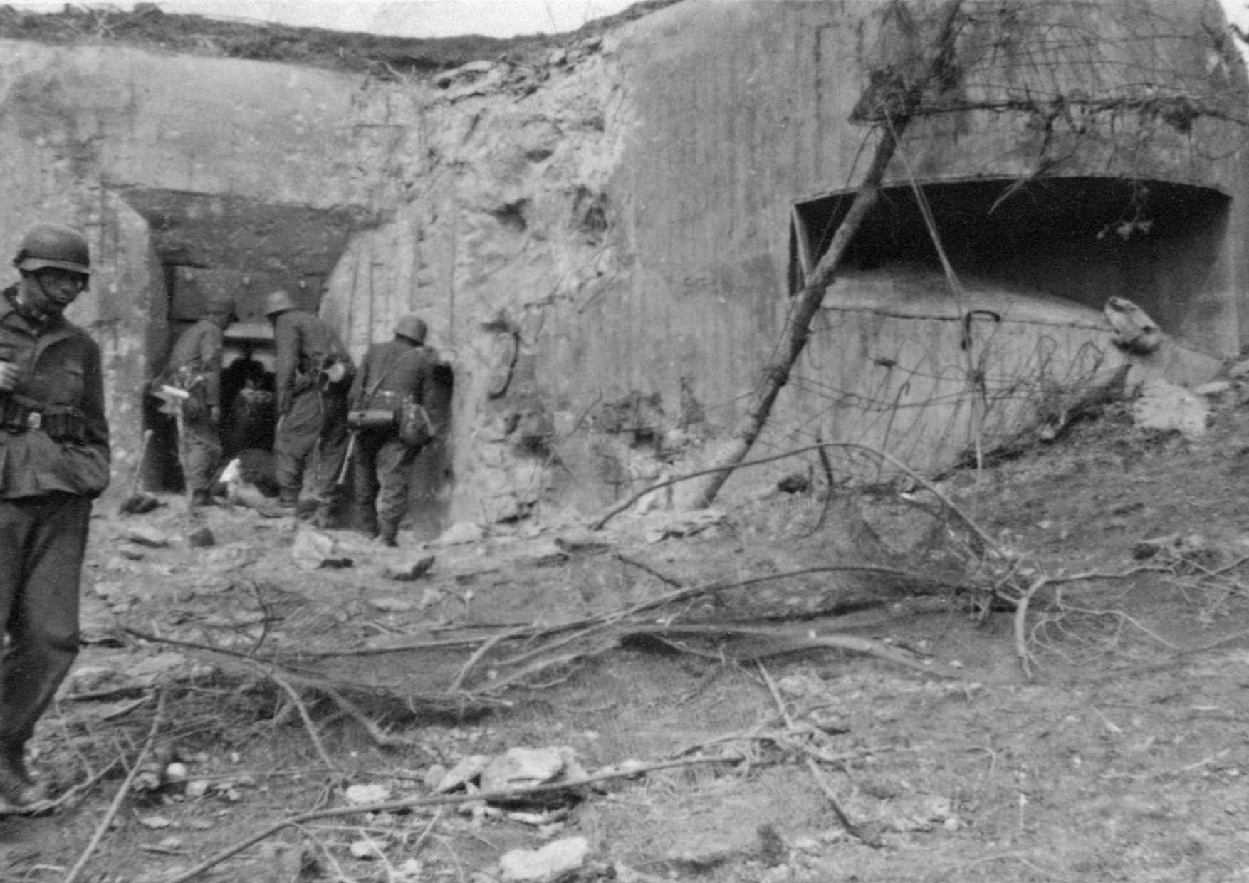 Περιοχή Σερρών, 6-7 Απριλίου 1941. Ομάδα Γερμανών καταδρομέων φωτογραφίζεται καθώς περιεργάζονται το πυροβόλο και το πυροβολείο κάποιου ελληνικού οχυρού του Υποτομέα Θύλακος, αμέσως μετά την κατάληψη του