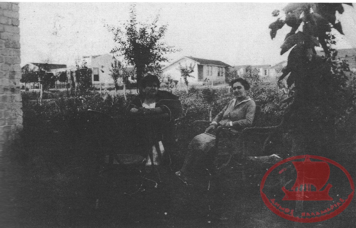 Αρετσού. Η κα. Σύρου και η κα. Αβραμίδου στην οικία Σύρου, στο βάθος τα προσφυγικά
